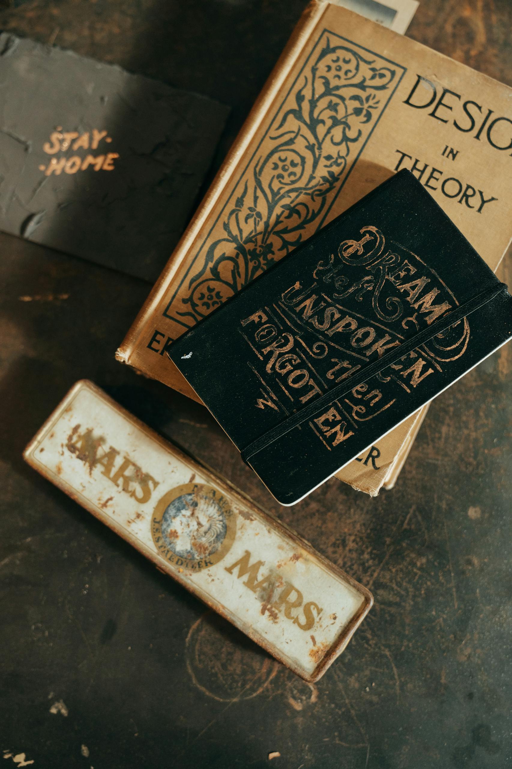 Overhead view of vintage books and stationery, featuring a rustic aesthetic with an old book and metal tag.